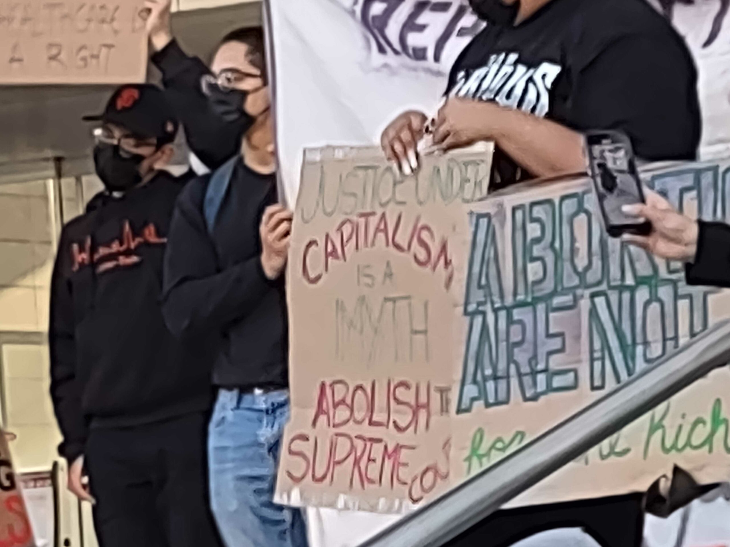 Protesters with signs, "Justice under capitalism is a myth. Abolish the supreme court"