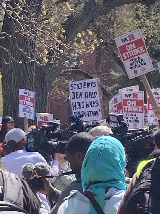 Students gather amid many media cameras with a sign reading students demand holloway's resignation!