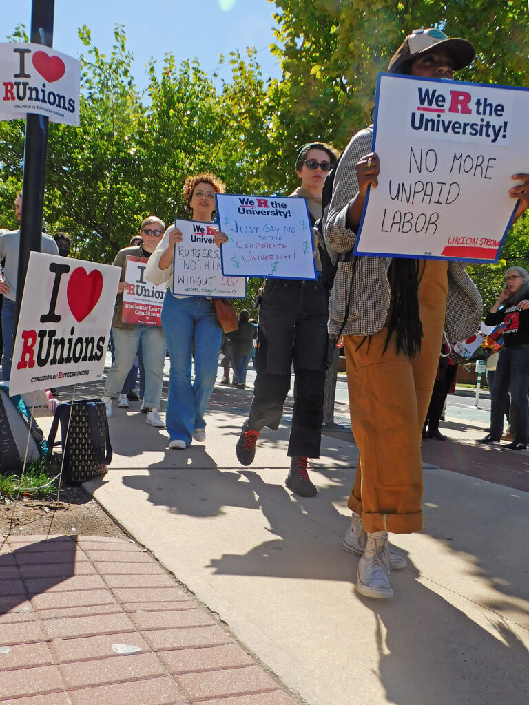 Picketers carry signs reading Union strong, We "R" the university, no more unpaid labor