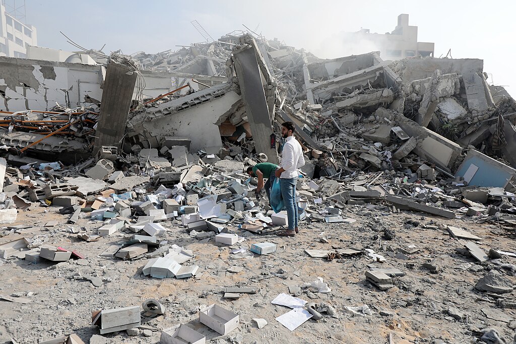 Two men stand in a pile of rubble.