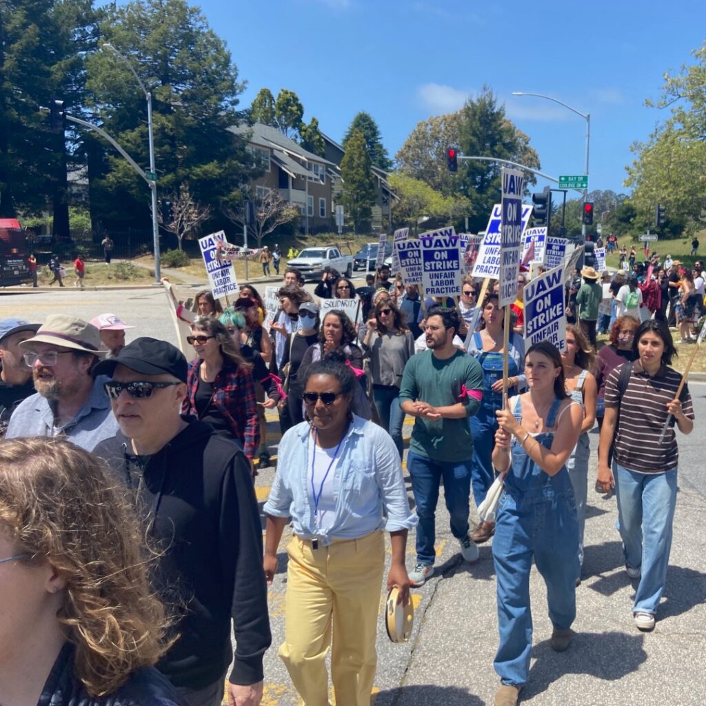 A crowd of marchers with UAW strike signs
