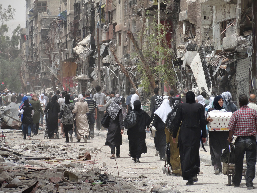 Scene from Yarmouk refugee camp, the less than one-square-mile camp populated by Palestinians, constructed in 1957. The photo shows the backs of a long line of refu