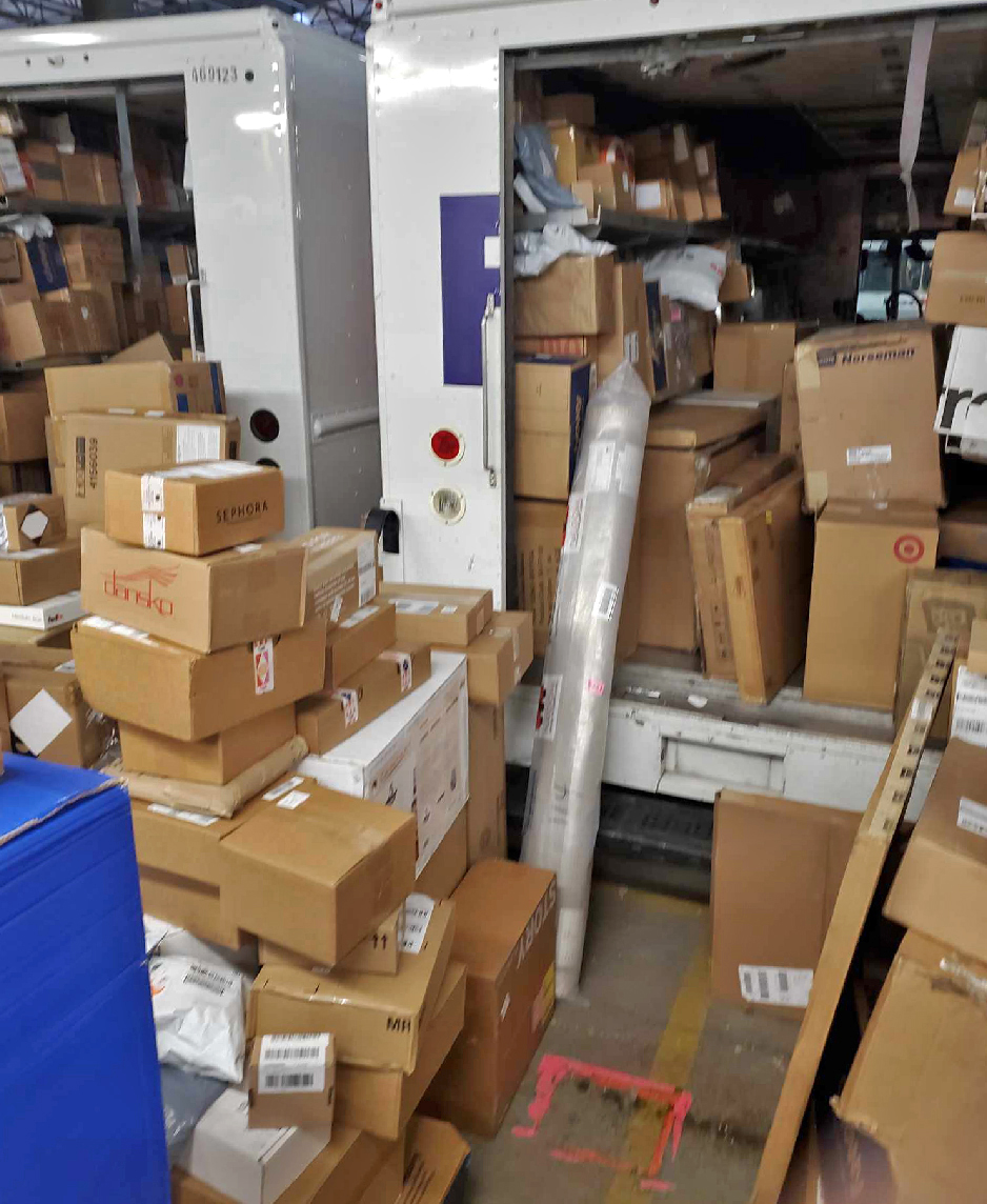 A pile of boxes and tubes in and around the back of trucks.