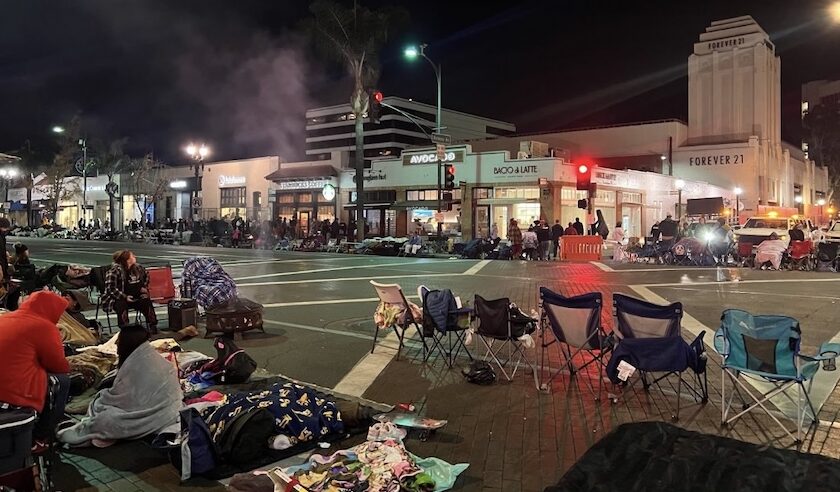 A line of folding chairs and individuals in sleeping bags and blankets awaiting the start of the Rose Parade pre-dawn, January 1, 2025. Photo by Teto.