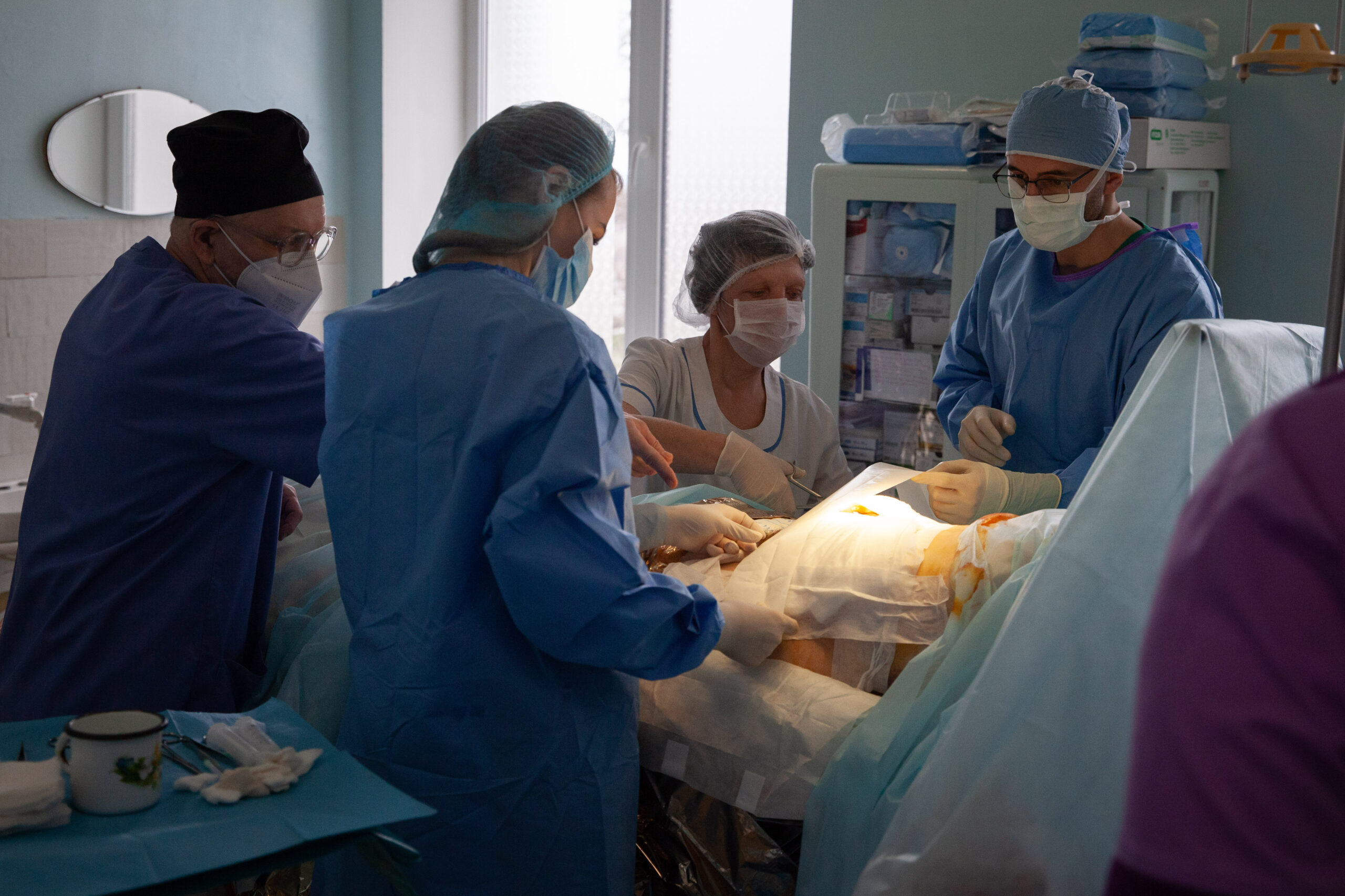 A photo of surgeons wearing masks standing over a patient they are operating on.