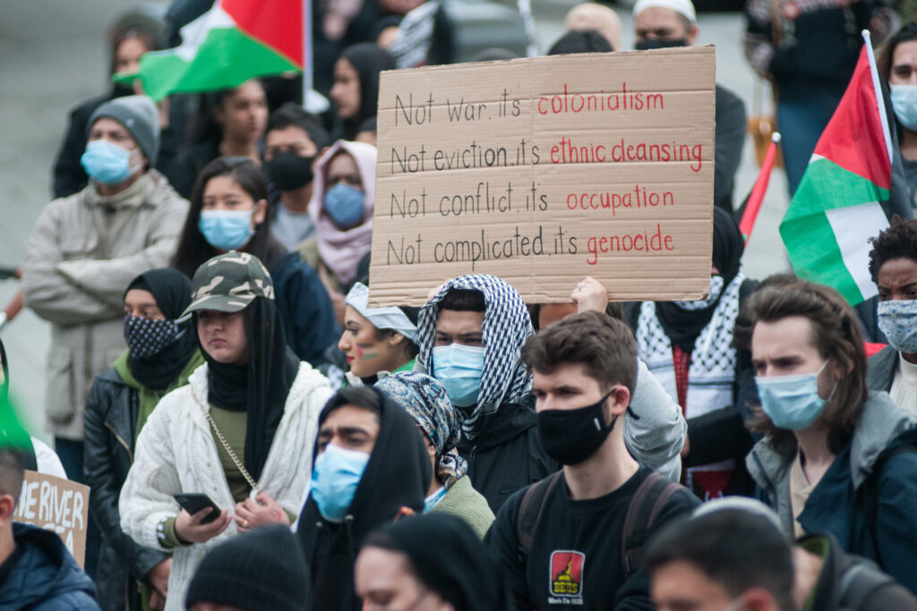 Palestinian solidarity protest. Sign reads "Not war, its colonialism; not eviction its ethnic cleansing; not conflict its occupation; not complicated its genocide."