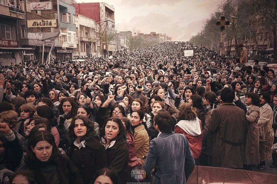 ​​A large number of Iranian women in casual dress, not wearing hijabs or head coverings and with many raising their fists take over a public street in Tehran.