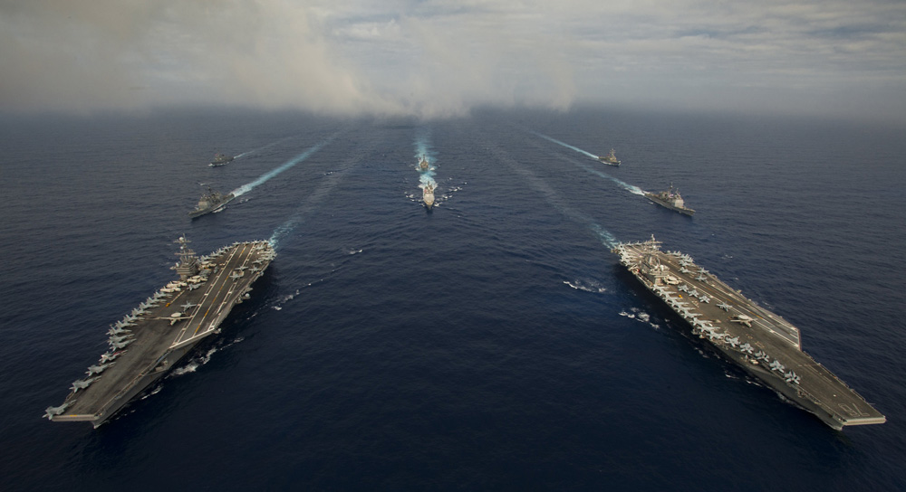 A photograph of the five aircraft carriers in the U.S. Seventh Fleet, on the ocean.