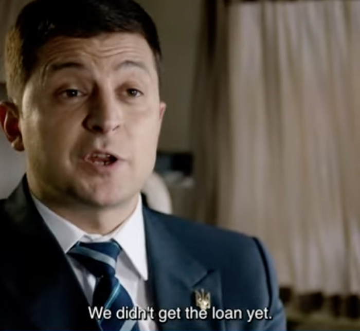 Screenshot of a TV close-up: A clean-shaven Volodymyr Zelensky says (in a subtitle), “We didn’t get the loan yet.”