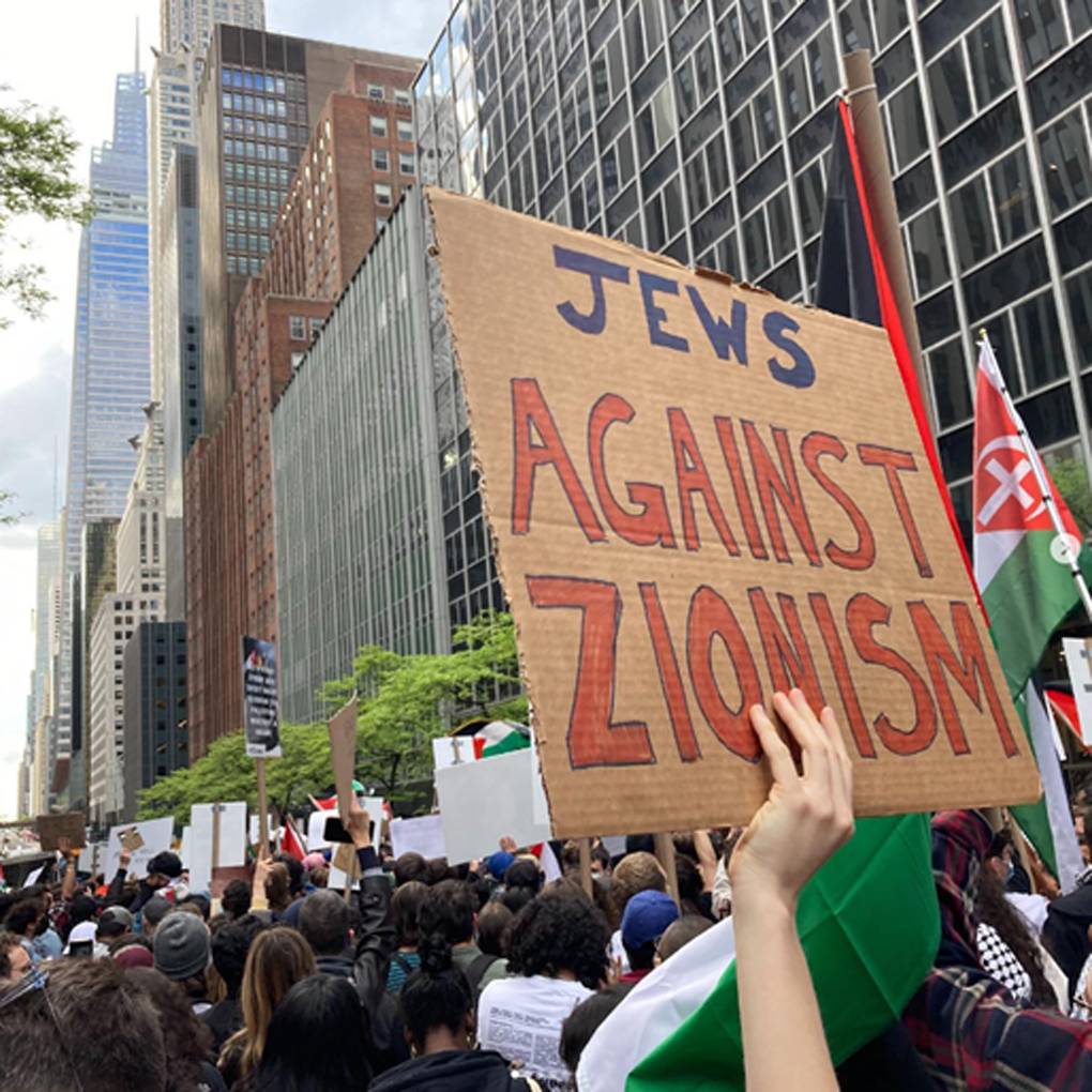 a protester holds a sign reading Jews Against Zionism