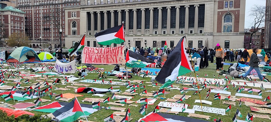 Rows and rows of signs and Palestinian flags on the university mall at Columbia University. A banner reads Gaza Solidarity Encampment.