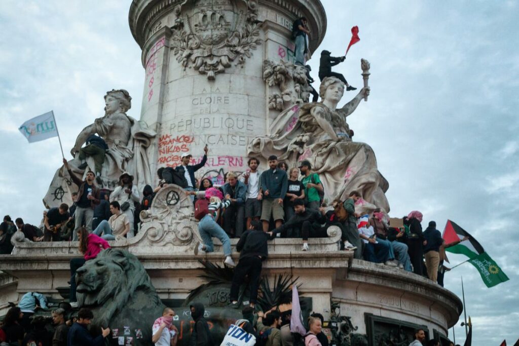 In the aftermath of the second round of parliamentary elections at a rally in Paris, France, demonstrators, carrying banners and the Palestinian flag, climb on the statue in the Place de la Republique. Photo by Martin Noda / Hans Lucas.