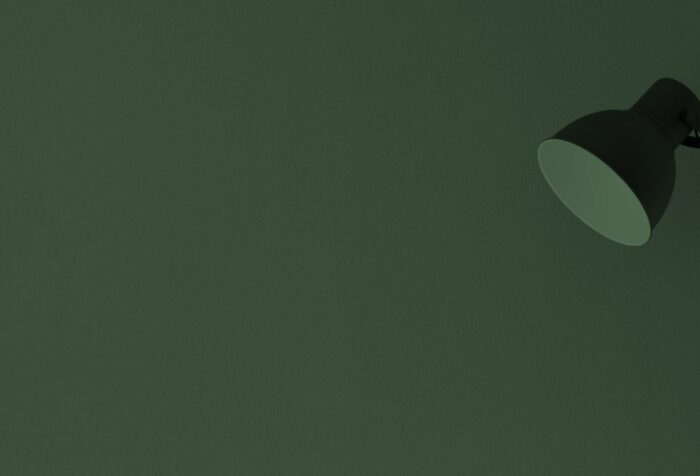 A plain dark green background with a black lamp on the right side.