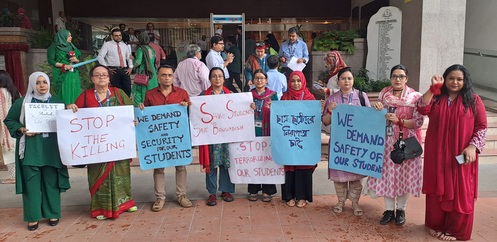 Eight women and one man stand with signs in English and Bengali.