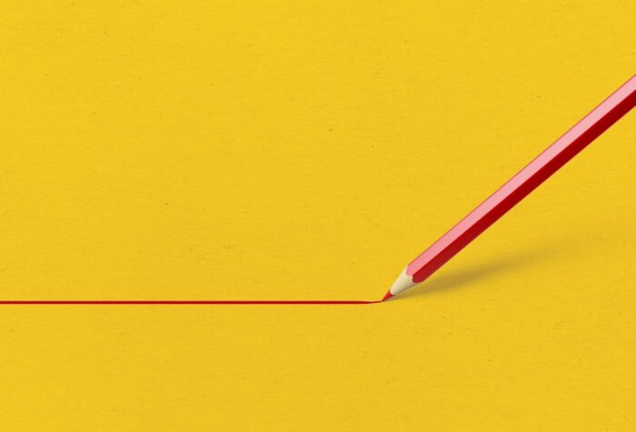 A red pencil draws a straight, red line from the left to the right of the image against a solid yellow background.