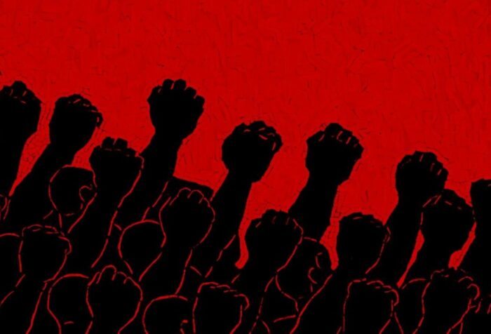 A red background, with a black silhouette of many fists, tilted rightward, raised into the sky.