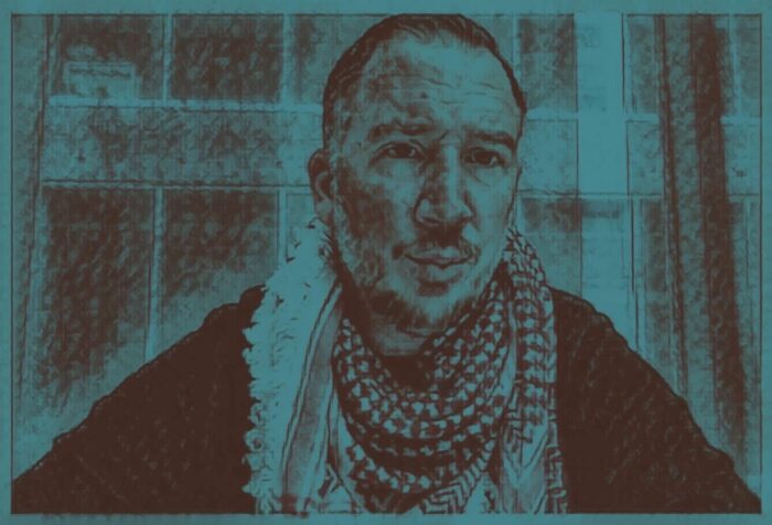 A picture of a person looking forward with a keffiyeh wrapped around their neck.