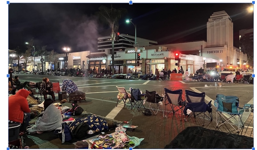 A line of folding chairs and individuals in sleeping bags and blankets awaiting the start of the Rose Parade pre-dawn, January 1, 2025. Photo by Teto. 