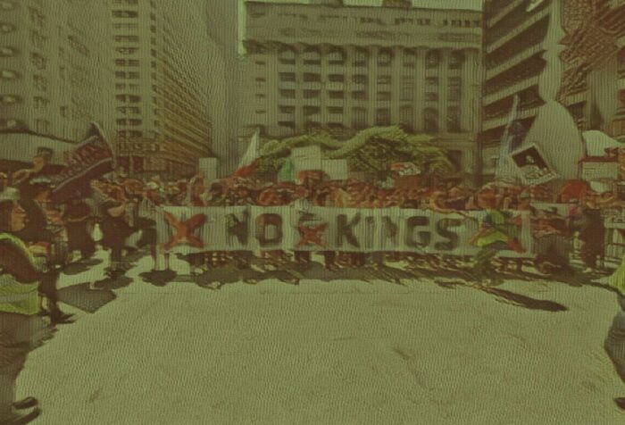 A protest crowd holds a banner that says NO KINGS.