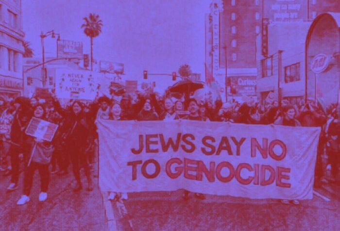 A photograph of a crowd holding a sign saying "Jews say no to genocide." Photo is filtered with a purple tint.