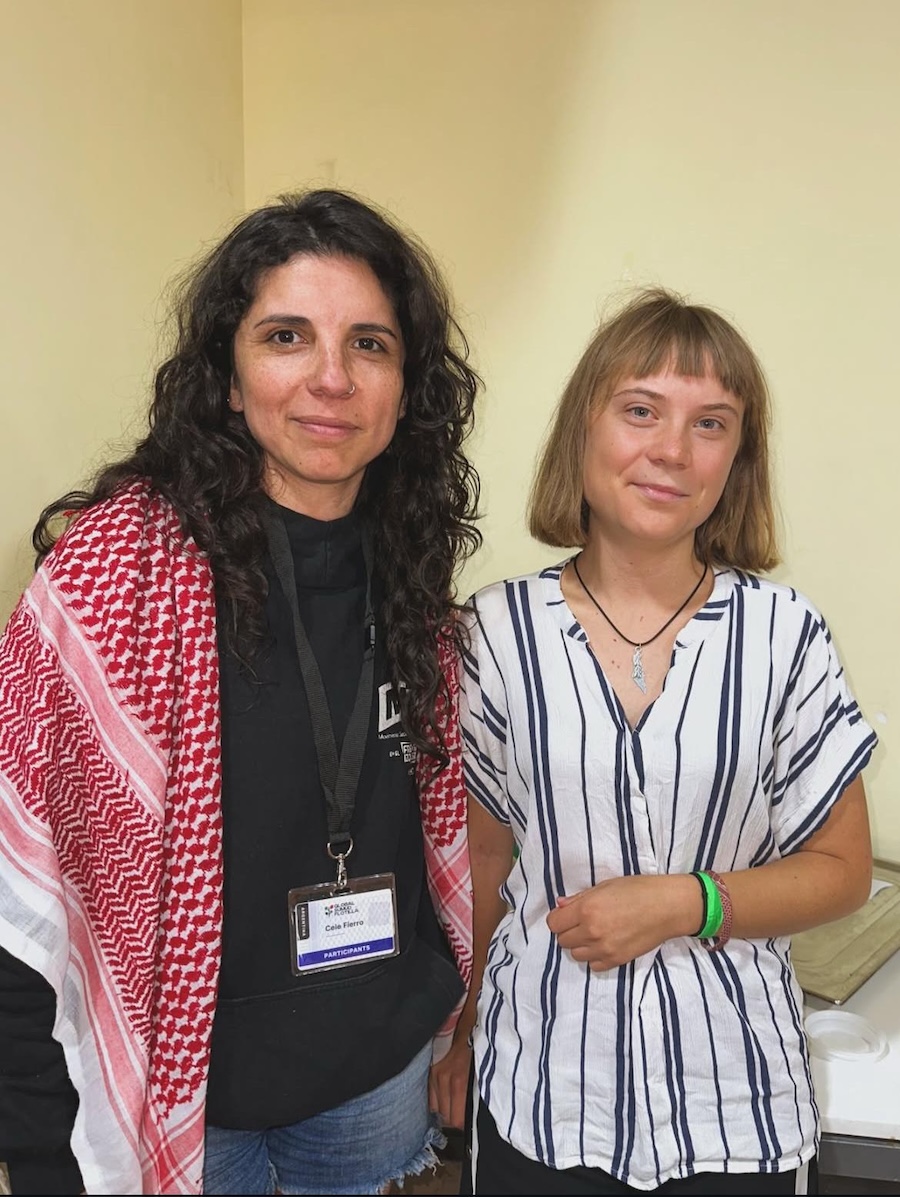 Cele Fierro, wearing a red keffiyeh, standing next to activist Greta Thunberg.