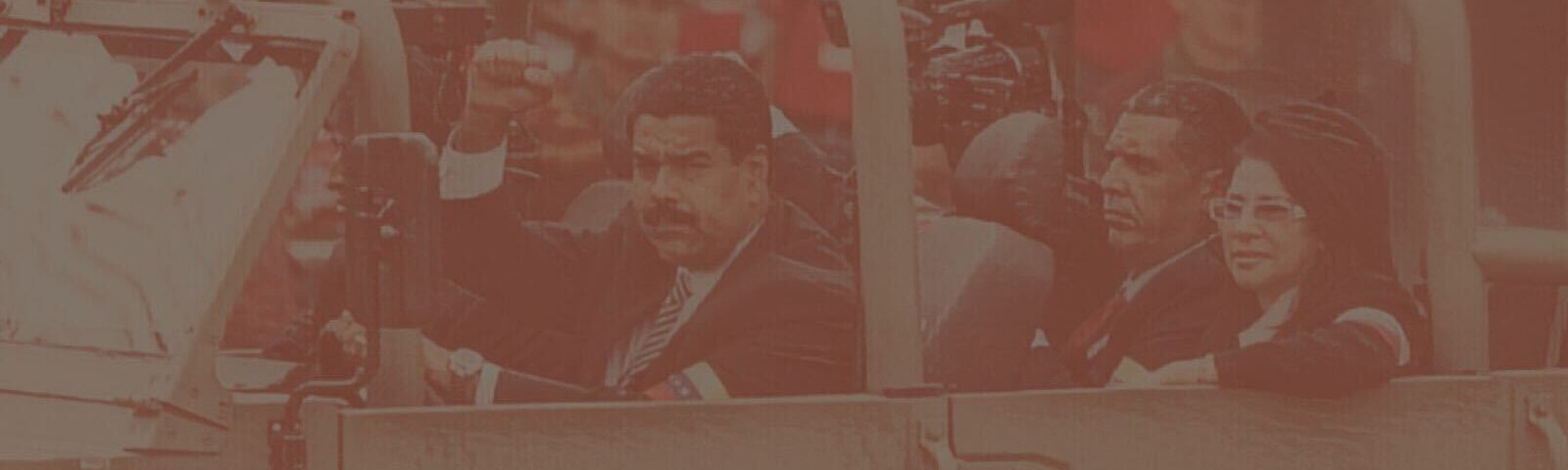 A photo of Nicolás Maduro driving an army car with others in it, holding his fist up, with a crowd of people behind. Photo is filtered with a faded brownish texture.