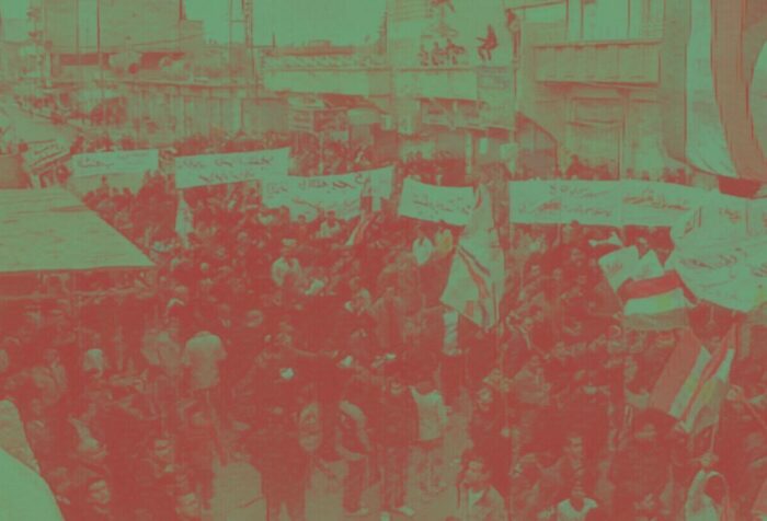 A green and red filtered photo of a crowd marching with signs written in Arabic.