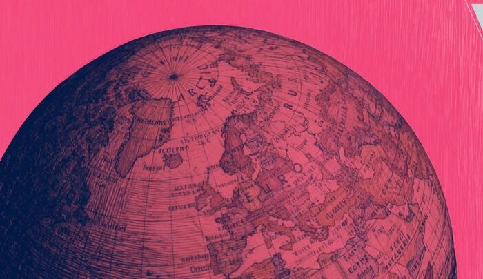A close-up of a globe against a pink background.