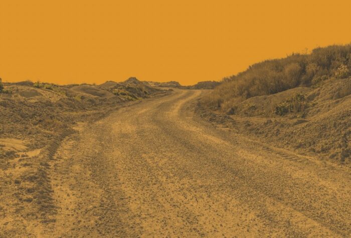 A yellow-filtered photo of a winding dirt road.