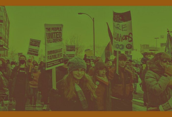 A green-tinted image of protestors holding signs