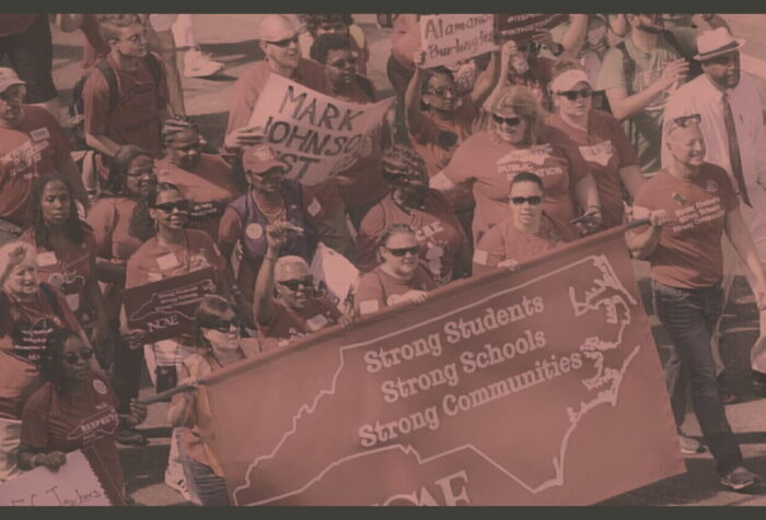 A crowd of teachers marching with signs.