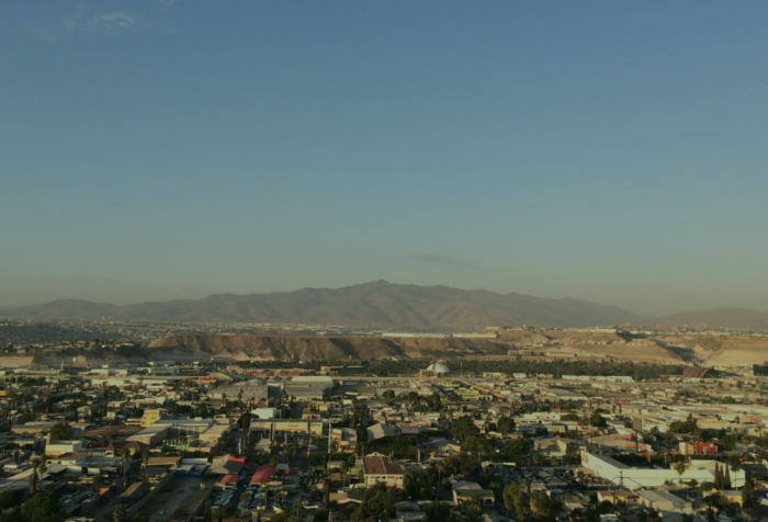 A landscape photo of buildings in Tijuana, mountains in the background, and the sky above.