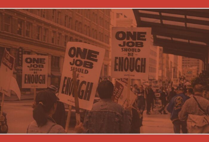 A red-tinted photo of people carrying signs reading "one job should be enough."
