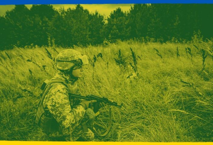 A soldier holding a gun in a field.