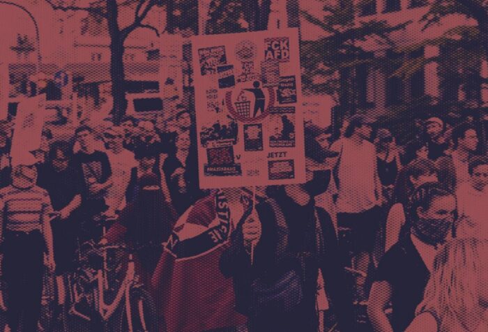 A crowd of protestors holding signs in German.