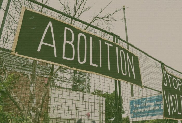 Signs on a fence that say "bolition" and "stop the violence"